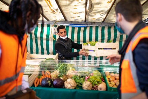 Un commerçant du marché donne une cagette de légumes aux bénévoles Biocycle.