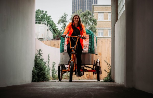 Une bénévole Biocycle conduisant le vélo triporteur, de face, en ville