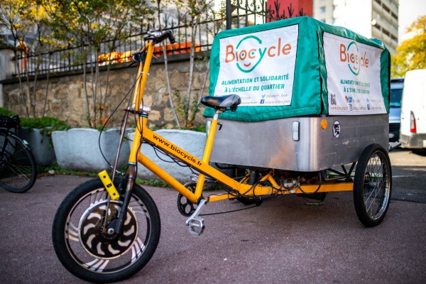 Un vélo triporteur Biocycle devant une grille.
