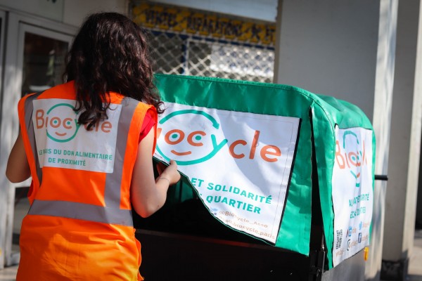 Une bénévole qui ouvre la bache d'un vélo triporteur Biocycle