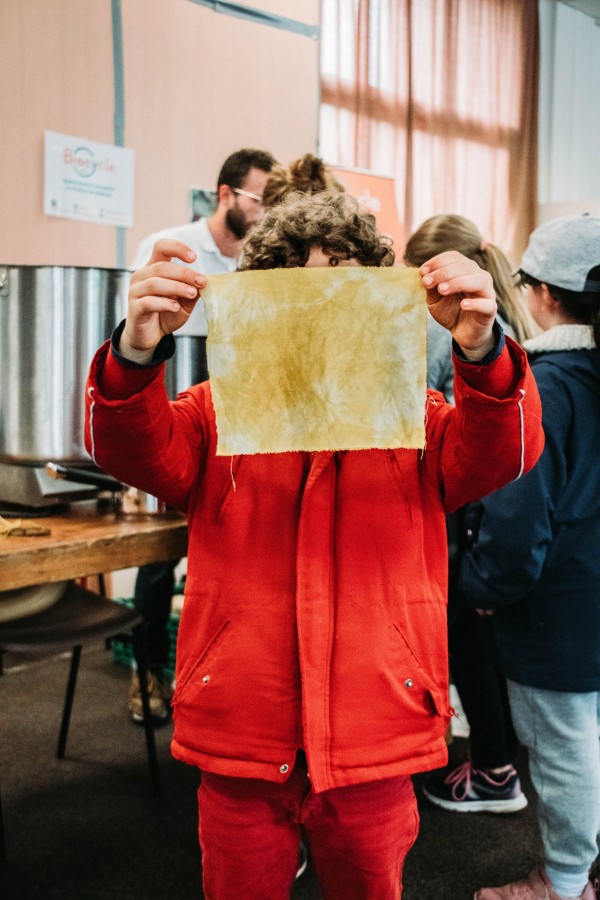 Un enfant montre un tissu coloré avec des colorants naturels issus des fruits et légumes