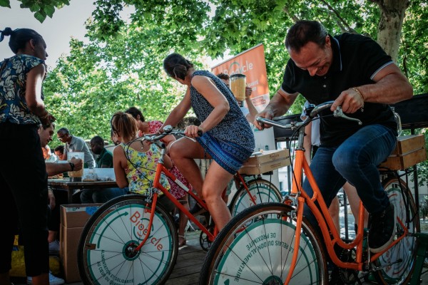 Une femme et un homme pédalent sur notre vélo mixeur durant une animation de sensibilisation à l'anti-gaspi