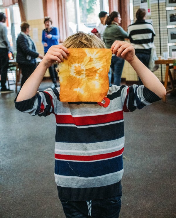 Un enfant montre un tissu coloré avec des colorants naturels issus des fruits et légumes