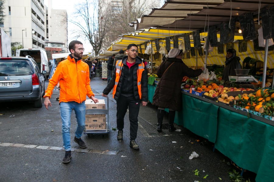 Deux bénévoles Biocycle sur un marché, tirant un diable avec des cagettes