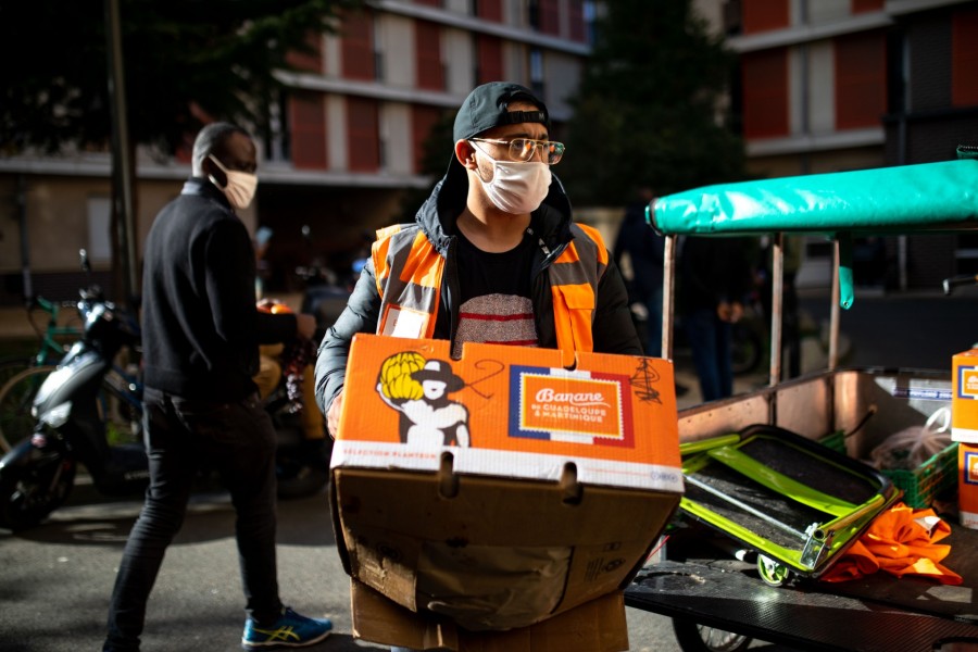 Un bénévole porte un carton, sur un marché